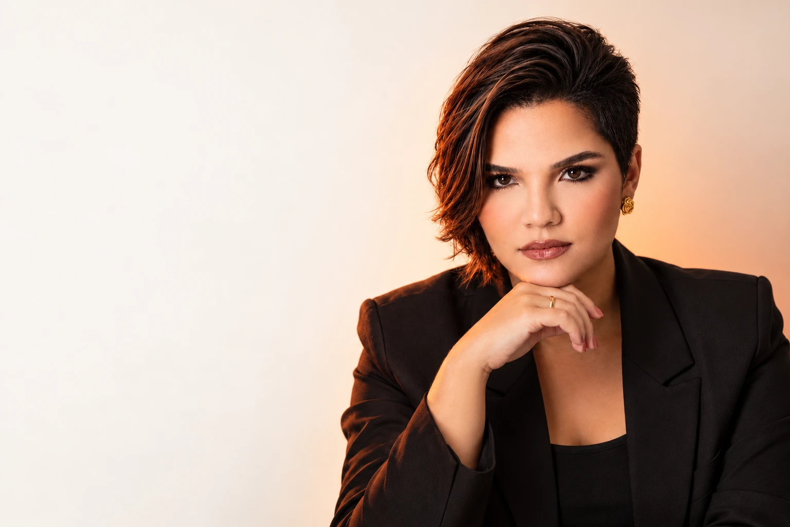 Emilly Kamile em retrato editorial, com blazer preto e luz quente